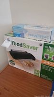 Box for the FoodSaver vacuum sealing system, showing brand, general product image, and contents.