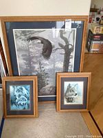 Three framed wildlife prints displayed together: a large bald eagle in flight, smaller wolves in blue tones, all with wooden frames.