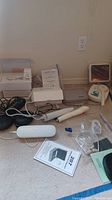 Lot items arranged on carpet including massage devices, electrotherapy units, cables, manuals, and plastic cases.