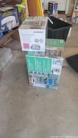 Photo showing boxed Designa mesh desk organizer and 4-tier rolling cart boxed in a garage setting