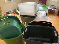 Photo showing a variety of plastic laundry baskets and storage bins including green, white, gray, and clear plastic containers.