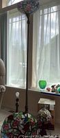 Tall floor lamp with stained glass floral shade next to a window