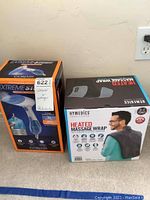 Photo of Conair Extreme Steam Garment Steamer and HoMedics Heated Massage Wrap boxes side by side.