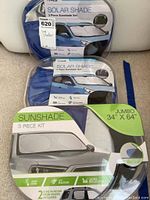 Three new jumbo-sized 3-piece sunshade kits in blue and transparent zippered cases showing front packaging with car illustration and product details.