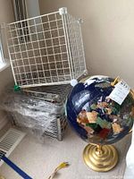 Full view of the wire storage organizer stacked with four drawers and wire basket, alongside the decorative blue lapis stone world globe on a brass stand.