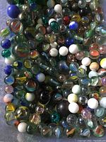 Close-up of various antique glass marbles with colorful swirl patterns, opaque and clear glass marbles.