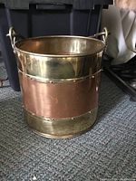Photo showing the full copper and brass bucket from the front, highlighting the studded border and metal handle.