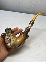 Front view of antique meerschaum pipe showing carved house design and amber mouthpiece.
