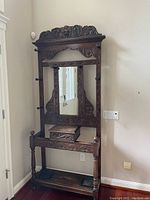 Full view of carved wood hall tree showing mirror, drawer and shelf