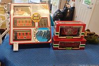 LGB train set components on blue padded surface including boxed passenger cars, boxed caboose with Santa design, and track pieces.