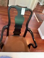 Front view of a single wooden dining chair showing the curved backrest and armrest design, upholstered brown seat, and Queen Anne style legs.