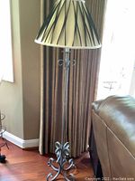 Full view of metal base floor lamp with cream shade featuring black stripes