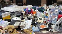 Wide view of entire lot showing mixed bottles, boxes, bags, and personal care items on table.