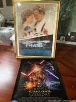 Framed Titanic poster and rolled Star Wars poster on floor