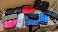 Lot of various purses, clutches, wallets and accessories arranged on cardboard boxes.