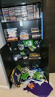 Photo of CDs and DVDs arranged on shelves in a black cabinet with Seahawks gear below