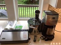 Photo showing FoodSaver vacuum sealer, vacuum bags, Anova sous vide immersion wand installed in stainless steel pot, and Cuisinart coffee maker.