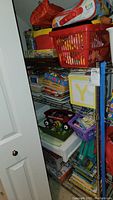 Shelf with plastic crate and various board games, books, and boxes stacked