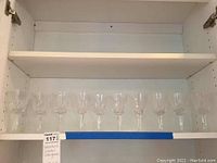 Full view of 10 Waterford Crystal wine glasses lined up on shelf showing clear cut crystal patterns