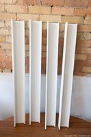 Four vertical white Ikea Mosslanda shelves showing side profile and mounting holes