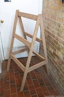 Full view of the wood blanket display stand showing the triangular frame and horizontal bars.