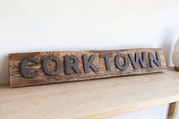 Front side view of the Corktown wooden sign showing weathered wood and metal letters against a plain background.