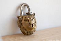 Front view of large brass lion head padlock with silver shackle.