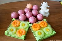 Lot showing two boxed sets of floral floating candles in orange and light green, ten spherical candles in pink and peach, and a white unicorn candle.