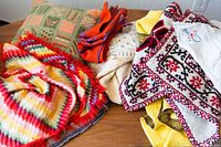 Lot of assorted pillowcases and linens laid on a table, showing varied embroidered and knitted designs.