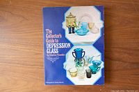 Front cover of the book showing title and various Depression Glass items in blue and amber shades.