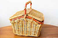 Front angle of wicker picnic basket showing woven wicker and handle.
