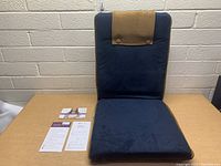 Front view of BonViVO Easy II Folding Chair with accompanying documentation on table.