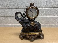 Front view of elephant mantle clock showing clock face, elephant figure with raised trunk, and ornate base