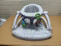 Front view of the Fisher Price baby seat showing padded fabric liner and attached toys.
