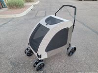 View of large pet stroller from a slight angle showing front mesh panel, wheels, and handle