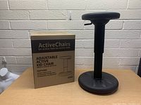 Photo of black hydraulic adjustable stool next to its original box labeled 'ActiveChairs Adjustable Active Kid Chair'