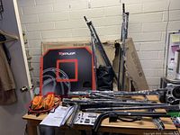 Photo of unassembled parts including metal frame pieces, basketball hoops with nets, instruction manual, basketballs, and backboard.