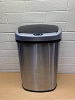 Front view of SensorCan automatic lid trash can showing stainless steel body and black lid.