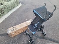 Front and side view of the Summer 3D Lite Mini stroller with original box in the background.
