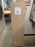 Photo of the packaging box with visible label and dimensions of the media stand.