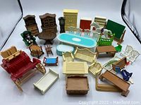 Photo showing a collection of assorted Playmobil furniture pieces including tables, chairs, cabinets, beds, a red carriage, and some figures.