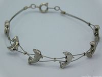 Silver tone double strand bracelet with six small dolphins along its length, shown against plain surface.