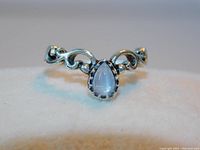 Front angle of the ring showing pear-shaped moonstone and filigree band.