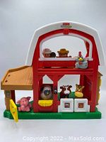 Front view of Fisher Price Little People barn with chicken on front and farmer and construction worker figures in window.