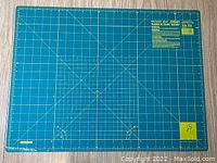 Front side of OLFA rotary cutting mat showing grid lines, measurement scales, model number, and care instructions.