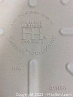 Close-up of the back of the stone showing embossed brand and series imprint: 'The Pampered Chef Family Heritage Stoneware Classics Collection USA'.