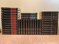 Full set of 36 Britannica volumes stacked and aligned to show leather bindings and spine text color-coded by section.
