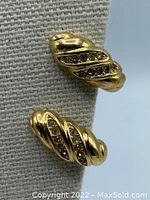 Close-up angled photo of earrings showing twisted design with two rows of rhinestones on each earring.