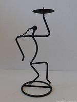 Blackened string iron dancing figure candleholder in a modernist abstract style, shown from side profile against plain background.