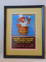 Full view of the framed vintage French print "La Vache qui rit" showing the entire artwork within a black wooden frame and pale yellow mat.